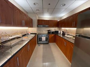 a kitchen with wooden cabinets and stainless steel appliances at Holiday Homes Amazing 2 Bedroom City Skyline View in Ajman 