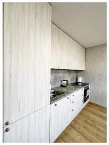 una cocina con armarios blancos y fregadero en Apartaments in the city centre en Kaunas