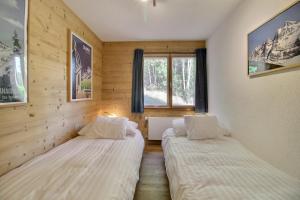 2 Betten in einem Zimmer mit Holzwänden und einem Fenster in der Unterkunft Cable Car 1min Walk, Fully Renovated In 2017 in Champéry