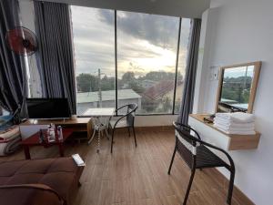 ein Wohnzimmer mit einem Schreibtisch und Stühlen sowie einem großen Fenster in der Unterkunft Ngoc An Hotel in Tây Ninh