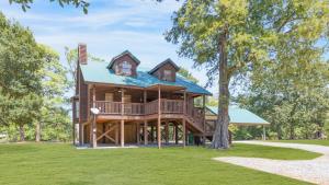 a large log house with a wrap around porch at Experience Louisiana, Cabin on Bayou Petite Anse in New Iberia