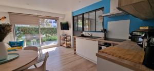 uma cozinha com paredes azuis e uma mesa e cadeiras em HOME ET HOLIDAY Le Chardonnay em La Baule