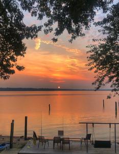 - un coucher de soleil sur un lac avec une table et des chaises dans l'établissement Waterfront Home with Private Beach, Stunning Views, à Middle River