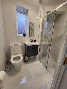 a white bathroom with a toilet and a shower at Cosy Studio in trendy Islington, w/private garden! in London