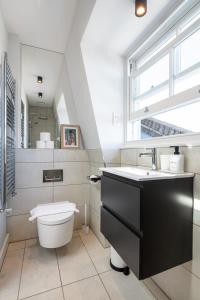 a bathroom with a toilet and a sink and a window at Notting Hill Apartments Collection in London