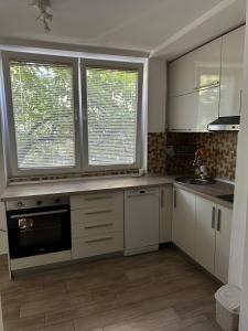 a kitchen with white cabinets and two large windows at 65m2 Apartment, 3 Rooms Skopje, Karpos in Skopje