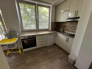 a kitchen with white cabinets and a table and two windows at 65m2 Apartment, 3 Rooms Skopje, Karpos in Skopje