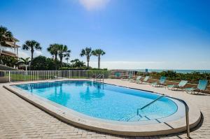 a large swimming pool with chairs and the ocean in the background at Sonrisa 1 in Clearwater Beach