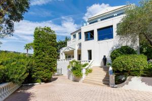 ein weißes Haus mit Treppen und Bäumen in der Unterkunft Belvedere - Villa Luxe Montfleury in Cannes