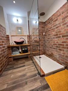 a bathroom with a glass shower and a brick wall at Apartman centrum Šturka in Martin