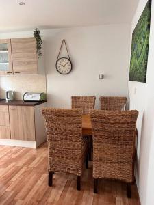 a dining room table with chairs and a clock on the wall at Apartman centrum Šturka in Martin