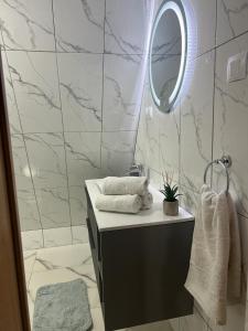La salle de bains est pourvue d'un miroir et d'un lavabo avec des serviettes. dans l'établissement Little House Bologa, à Bologa
