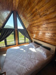 Bett in einem Zimmer mit einem großen Fenster in der Unterkunft Little House Bologa in Bologa