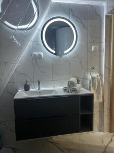 ein Bad mit einem Waschbecken und einem Spiegel in der Unterkunft Little House Bologa in Bologa