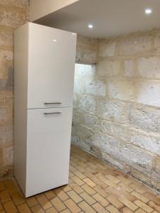 um frigorífico branco num quarto com uma parede de tijolos em Maison au cœur de la Ville. em Saint-Gilles
