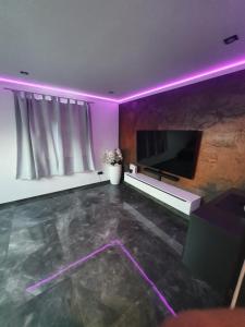 ein Wohnzimmer mit einem Flachbild-TV und violetten Lichtern in der Unterkunft Los Angeles Apartment in Paderborn