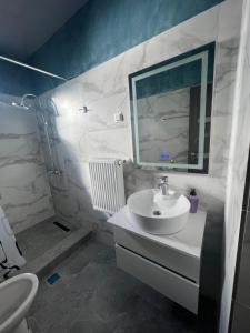 a white bathroom with a sink and a mirror at Sipotul Apelor in Domneşti