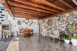 uma sala de estar com uma parede de pedra e uma mesa e cadeiras em Finca de los Abuelos em Guatiza