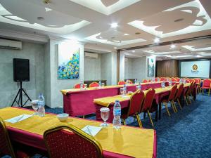 a conference room with tables and chairs and a screen at Sapphire Sky Hotel & Conference in Serpong