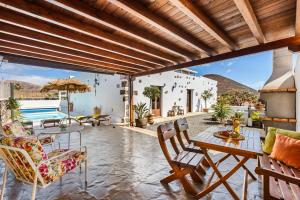 een patio met een tafel en stoelen en een zwembad bij Finca de los Abuelos in Guatiza