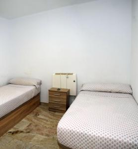 a bedroom with two beds and a dresser in it at Apartamentos Atlas Terrassa II in Terrassa