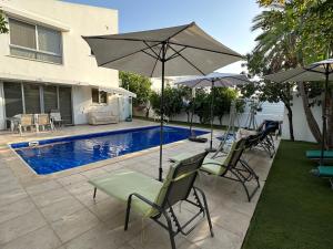 patio con sedie e ombrellone accanto alla piscina di Villa Victoria a Larnaka
