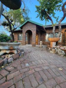 a brick house with a stone patio in front of it at Flamboyant Guesthouse in Bela-Bela