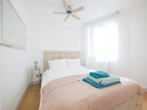 1 dormitorio blanco con 1 cama y ventilador de techo en Chelsea Cloisters en Londres
