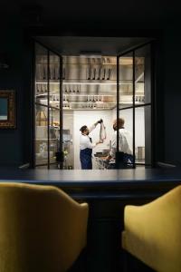 two chefs in a kitchen preparing food in a refrigerator at Caffè delle Rose Les Chambres in Verbania