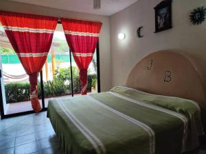 a bedroom with a bed with red curtains and a window at Hotel J.B. in Zihuatanejo