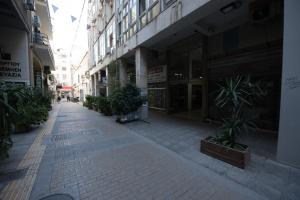 an empty city street with potted plants and buildings at Rob Venture Suites at the central of ATHENS city in Athens