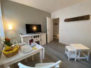 a living room with a white table and a television at Fischbude in Eckernförde