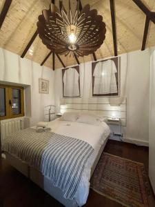 Un dormitorio con una cama grande y una lámpara de araña. en CASA DOS FALCÕES casa rural de construção tradicional, en Fajã da Ovelha