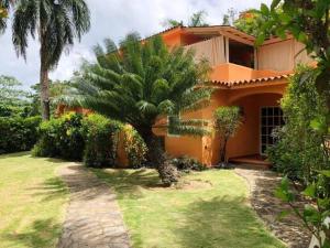 a house with a palm tree in front of it at Hotel - Residencial Madrugada in Las Terrenas