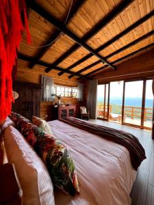 a bedroom with a large bed with a view of the ocean at LA PERLA FINCA HOTEl- Cabaña Esmeralda in Gigante
