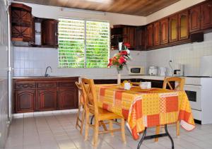 a kitchen with a table with a vase of flowers on it at Villa Des Sources Chaudes in Bouillante