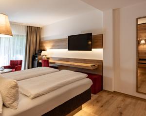 a hotel room with two beds and a flat screen tv at Hotel & Chalets Lampllehen in Marktschellenberg