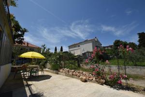 eine Terrasse mit einem Tisch, einem gelben Regenschirm und Blumen in der Unterkunft House Periska in Mrljane