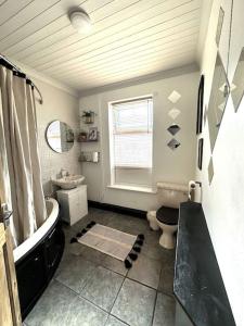 a bathroom with a tub and a toilet and a sink at Leeds Cosy House in Leeds