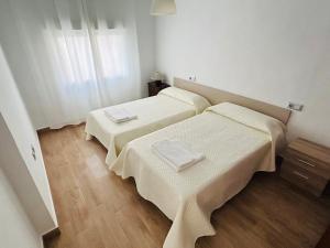 2 letti in una camera con pareti bianche e pavimenti in legno di Casa Quiteria a La Aljorra