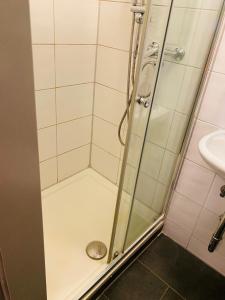 una ducha con una puerta de cristal junto a un lavabo en Hotel SuvaNa, 