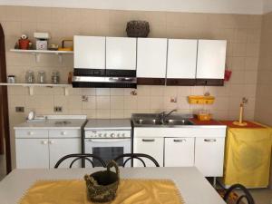 cocina con armarios blancos, mesa y fregadero en Liammare, en Mondragone