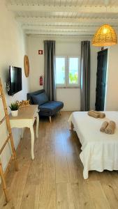 Zimmer mit 2 Betten, einem Tisch und einem Sofa in der Unterkunft Cantinho de Milfontes in Vila Nova de Milfontes