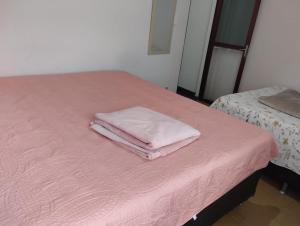2 toallas sentadas encima de una cama rosa en Andres Home casa H, en Governador Valadares
