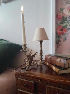 una vela sobre una mesa con una lámpara y libros en Rose's room en Saint-Léonard