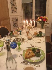 una mesa con platos de comida y velas. en Rose's room en Saint-Léonard
