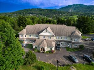 an aerial view of a large house with a parking lot at Splendid Mountain View Condo with Pool, BBQ & Terrace - Water Park, MTB, Cycling, Golf! in Bromont