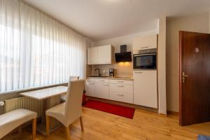 a kitchen with white cabinets and a table and chairs at Pension Nordlicht in Esens