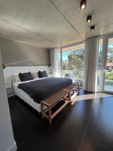 1 dormitorio con cama grande y banco de madera en INN Carilo en Cariló