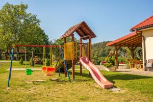 a playground with a slide and swings in a yard at Zielona Plaża in Bereżnica Wyżna +2 photos